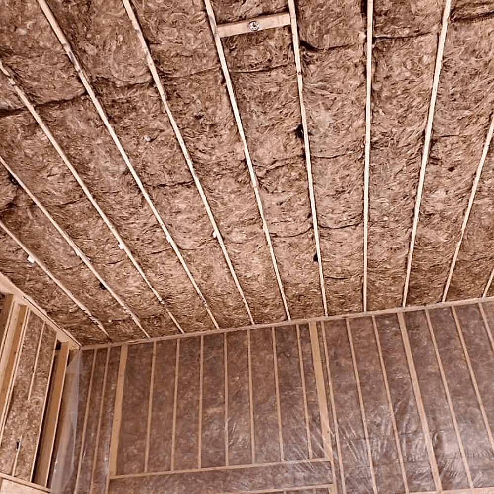 Ceiling joists with batt insulation fitted between them, the framing still exposed.