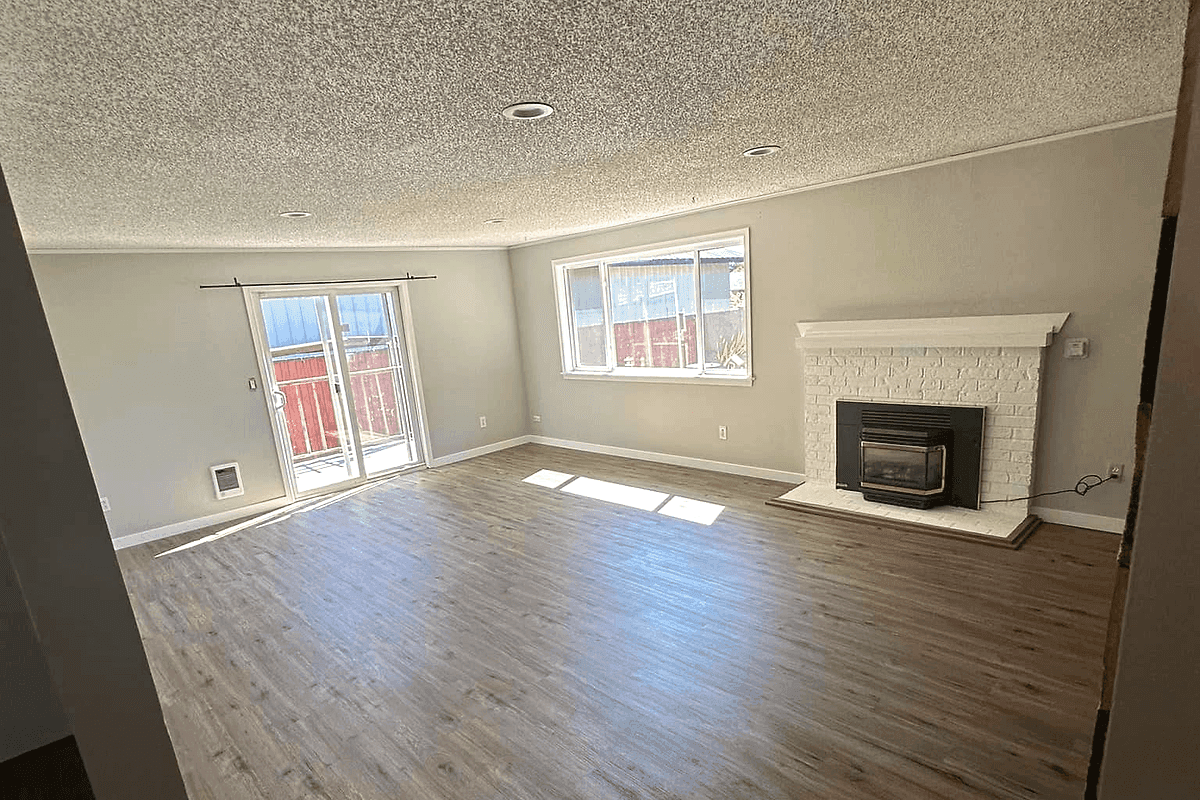 A finished living room with a fireplace and large windows.