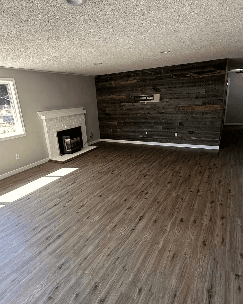 A finished living room with a fireplace and a reclaimed-wood accent wall.